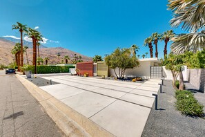 A modern residential area with a driveway leading to a gated entrance, surrounded by palm trees and a mountain in the background. - Classic, mid-century modern home w/ mtn views, private pool and spa - dogs OK (Palm Springs)