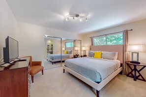 Quarto de hotel moderno com uma cama grande, uma mesa com televisão, uma cadeira e um espelho.