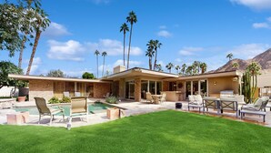 A modern house with a swimming pool, outdoor seating, and palm trees. - Exquisite retreat with pool, spa, fireplace, golf & mountain view, dog-friendly! (Indian Wells)