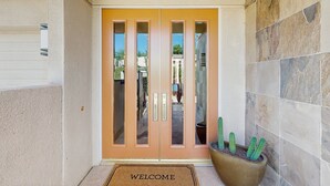 A hotel entrance with a double door, a welcome mat, and a potted cactus. - Exquisite retreat with pool, spa, fireplace, golf & mountain view, dog-friendly! (Indian Wells)