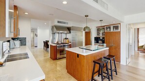 A modern kitchen with a central island, stainless steel appliances, and wooden cabinetry. - Exquisite retreat with pool, spa, fireplace, golf & mountain view, dog-friendly! (Indian Wells)