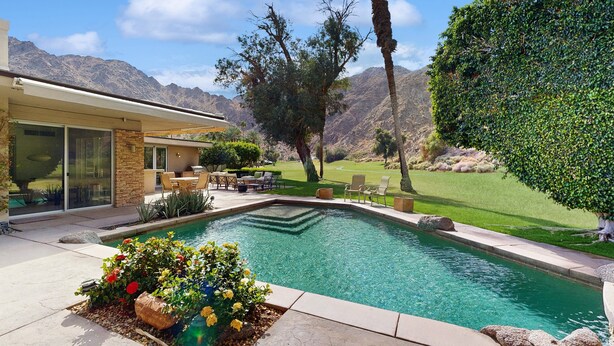 A swimming pool with a stone border, surrounded by a patio area with outdoor furniture. - Exquisite retreat with pool, spa, fireplace, golf & mountain view, dog-friendly! (Indian Wells)