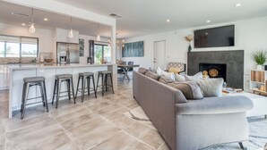 Een moderne keuken met een centraal eiland, barkrukken en hanglampen.