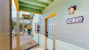 A house with a number '5020' on the wall, a door, and a small porch area. - Two-story mountain view retreat with two primary suites & ideal layout (Flagstaff)