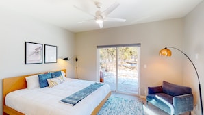 A bedroom with a bed, a ceiling fan, a sofa, a floor lamp, and a view of the outdoors. - Two-story mountain view retreat with two primary suites & ideal layout (Flagstaff)