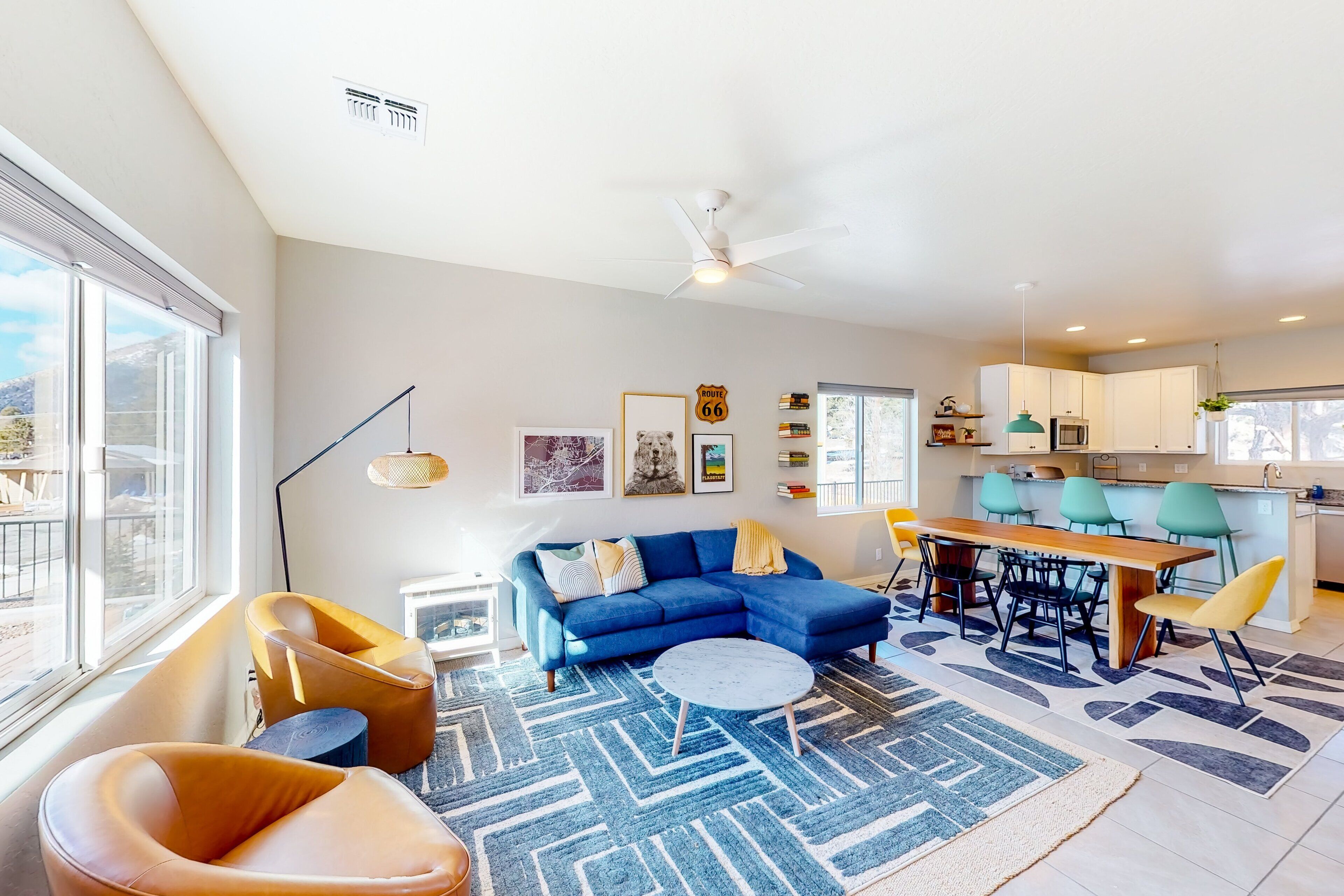 A modern living room with a blue sofa, a round coffee table, and a dining area with a wooden table and chairs.