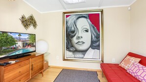 Ein Wohnzimmer mit Flachbildfernseher, einem roten Sofa, einem gerahmten Kunstwerk und einem Holzkabinett.
