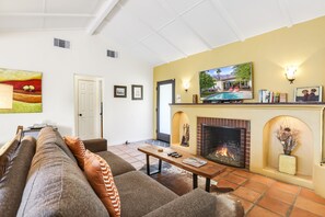 Una sala de estar con chimenea, televisión y un sofá.