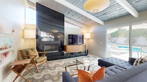 Un salon moderne doté d’une cheminée, de sièges confortables et d’une grande fenêtre donnant sur une piscine.