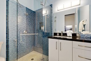 Une salle de bain moderne avec une douche à parois de verre, un lavabo avec un miroir et des toilettes.