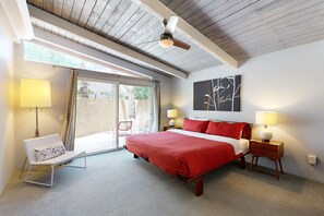 Une chambre à coucher avec un grand lit, une chaise, une table de chevet et un ventilateur de plafond.