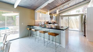Une cuisine moderne avec un îlot central, des tabourets de bar et une vue sur une piscine.