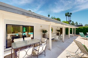 Ein Terrassenbereich im Freien mit einem Pool, der mit Glas umgeben ist, Liegestühlen und einem Esstisch mit Stühlen.