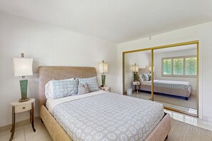 Quarto com uma cama, duas mesas de cabeceira, um espelho e uma janela.