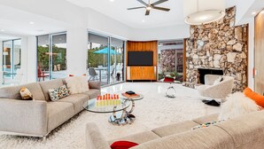 A modern living room with a sofa, coffee table, and a fireplace. - Mid-century modern estate with a pool, hot tub, gourmet kitchen, and fireplace (Palm Springs)