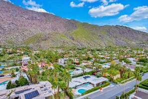A residential area with houses, palm trees, and a mountain in the background. - Mid-century modern estate with a pool, hot tub, gourmet kitchen, and fireplace (Palm Springs)
