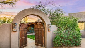 A gated entrance with a stone archway, a wooden gate, and a small statue of a cat. - Tucson ranch home with private pool, hot tub, gourmet kitchen, & patio (Marana)