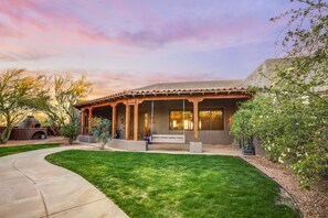 A modern house with a covered patio, a lawn, and a brick oven.