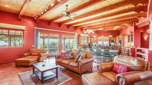 A spacious living area with leather sofas, a coffee table, and a ceiling fan. - Tucson ranch home with private pool, hot tub, gourmet kitchen, & patio (Marana)