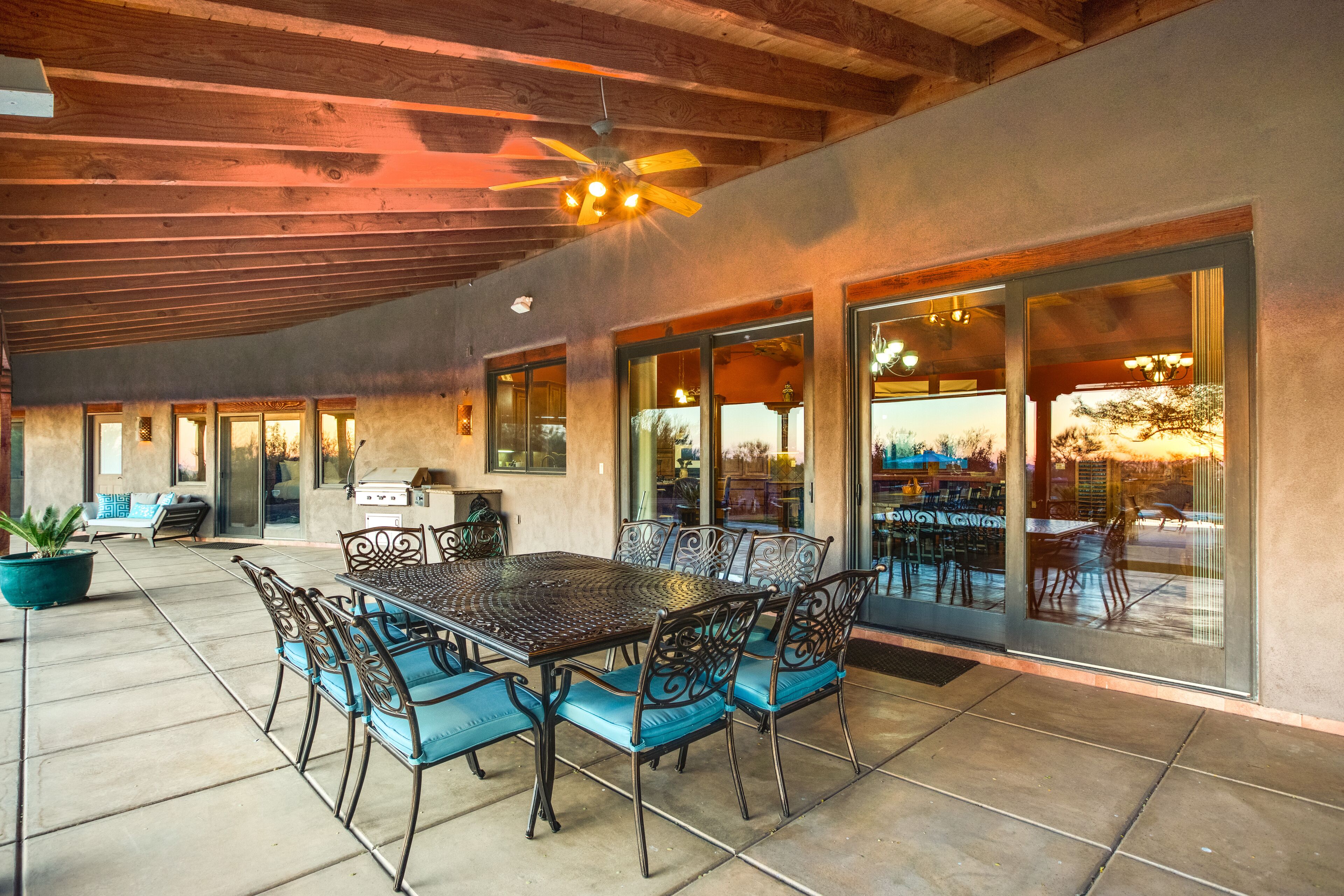 An outdoor patio with a dining table and chairs, a ceiling fan, and a view of the outside.