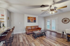 A spacious living room with a leather sofa, a coffee table, and a dining area with bar stools.