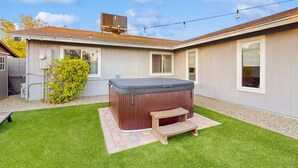 Un bain à remous dans un jardin, avec une terrasse en bois et une petite table.