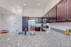 Una cocina moderna con encimeras de granito, electrodomésticos de acero inoxidable y armarios de madera oscura.