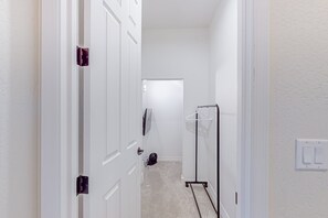 A hallway with white walls, a door, a coat rack, and a light switch. - Elegant home with mountain views, fireplace & grill (Flagstaff)