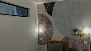 Una camera da letto moderna con un letto, una sveglia a parete, uno scaffale con una pianta e arte astratta alle pareti.