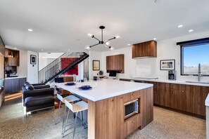 A modern kitchen with a central island, wooden cabinets, and a built-in oven. - Desert stunner in Joshua Tree with mountain view - near town & park entrance (Joshua Tree)