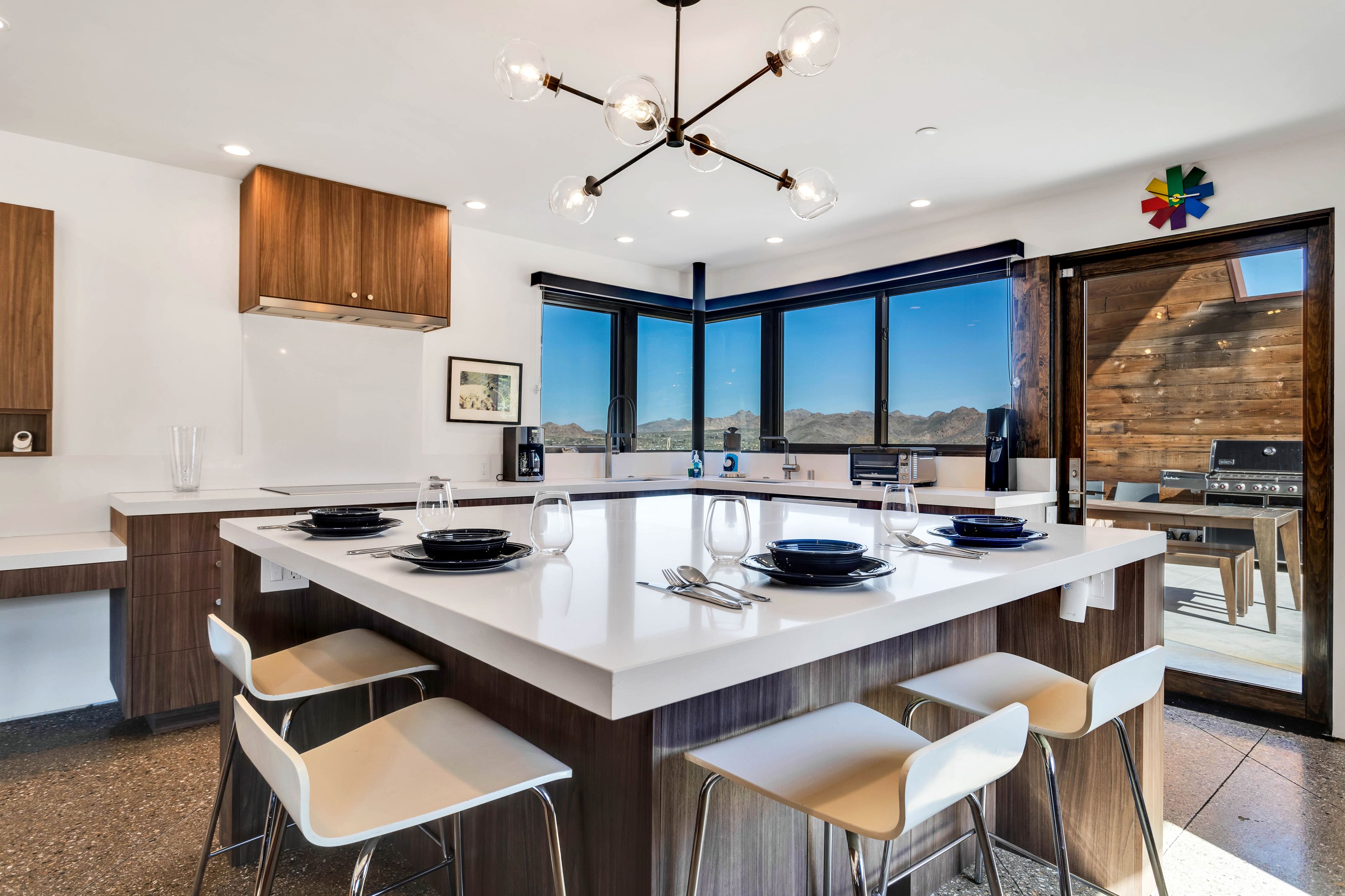 A modern kitchen with a large island, bar stools, and a view of the mountains.