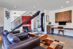 Ein modernes Wohnzimmer mit Ledersofas, einem Couchtisch und einer Treppe mit rotem Akzent.