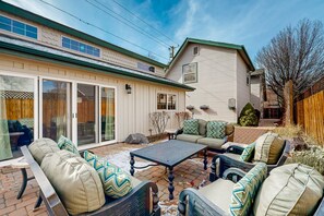 Eine Terrasse mit Gartenmöbeln, einer Schiebetür und einem überdachten Bereich.