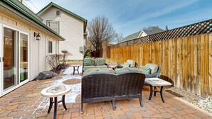 A patio with a sofa, two tables, and a wooden fence.