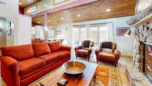 A spacious living room with a red sofa, leather armchairs, and a large wooden coffee table.