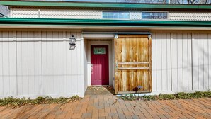 A building with a red door, a wooden gate, and a brick pathway leading to the entrance.