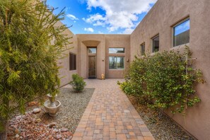 A courtyard with a brick pathway, a door, and a small statue. - Beautiful contemporary home with gorgeous views, private pool, & gas grill (Marana)