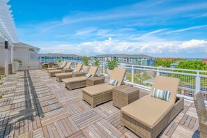 Eine Terrasse mit Korlounge-Stühlen und einem weißen Geländer.
