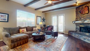 A living room with a sectional sofa, a round coffee table, a fireplace, and a ceiling fan. - Elegant house with great outdoor space, private pool & spa - 3BR - #066636 (La Quinta)