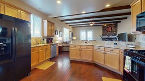 A kitchen with wooden cabinets, a black refrigerator, a stove, and a microwave. - Elegant house with great outdoor space, private pool & spa - 3BR - #066636 (La Quinta)