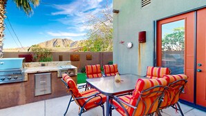 An outdoor patio with a grill, striped chairs, and a table. - Elegant house with great outdoor space, private pool & spa - 3BR - #066636 (La Quinta)