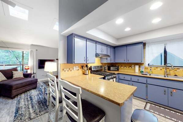 Una cocina moderna con gabinetes azules, una isla central y un comedor con sofá y sillas.