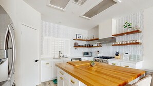 Een moderne keuken met witte kasten, een houten eiland en ingebouwde planken.