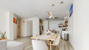 Een moderne woonkamer met een houten eettafel, witte stoelen en een bank.