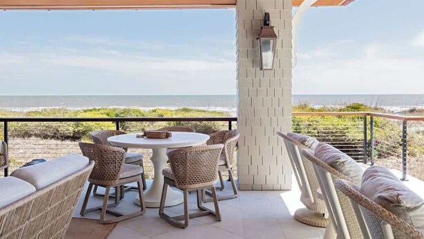 Una terrazza con mobili in vimini, un tavolo rotondo e vista sull'oceano.