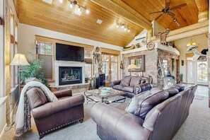 A spacious living room with leather sofas, a fireplace, and a ceiling fan. - Beautiful Sedona home with large country kitchen & amazing, 280-degree views (Sedona)