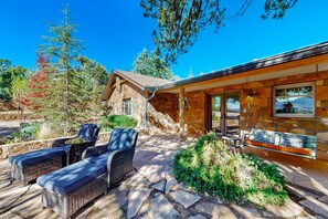 A stone building with a stone exterior, a covered patio with wicker furniture, and a view of the surrounding landscape. - Beautiful Sedona home with large country kitchen & amazing, 280-degree views (Sedona)