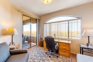 Ein Hotelzimmer mit Schreibtisch, Stuhl und einem großen Fenster mit Blick.