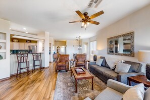 A spacious living area with a wooden floor, a ceiling fan, a sofa, and a coffee table. - Open & bright condo with WiFi, W/D, pool, hot tub & panoramic views (Oro Valley)