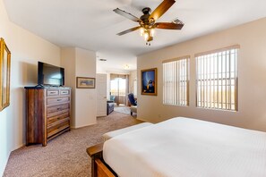 Une chambre à coucher avec un lit, une commode, un ventilateur de plafond et un téléviseur.